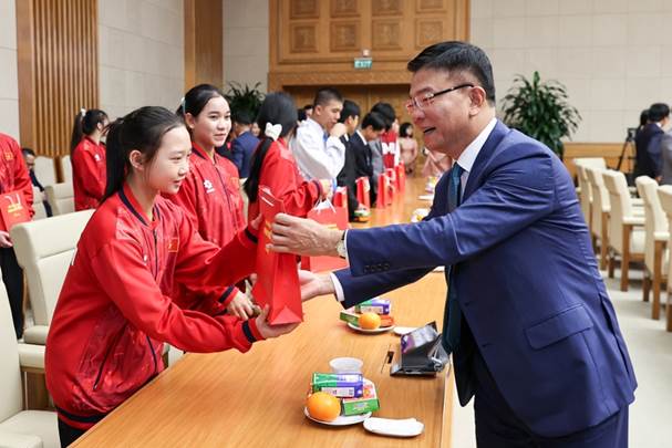 A person handing a red packet to a child Description automatically generated